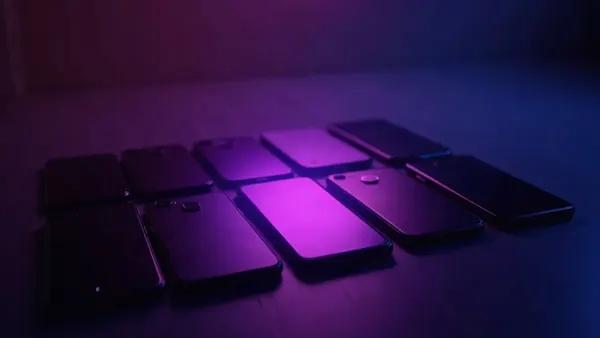 Meerdere smartphones op een rij, een paarse spot op de middelste (illustratie bij het artikel)